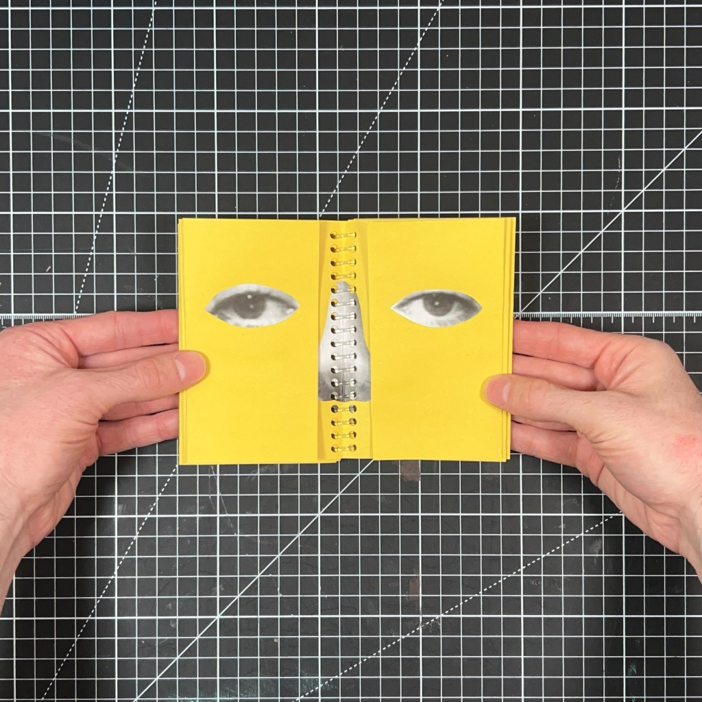 Open-eye interior spread of the yellow spiral-bound zine Blink and You’ll Miss It, held above a black cutting mat.